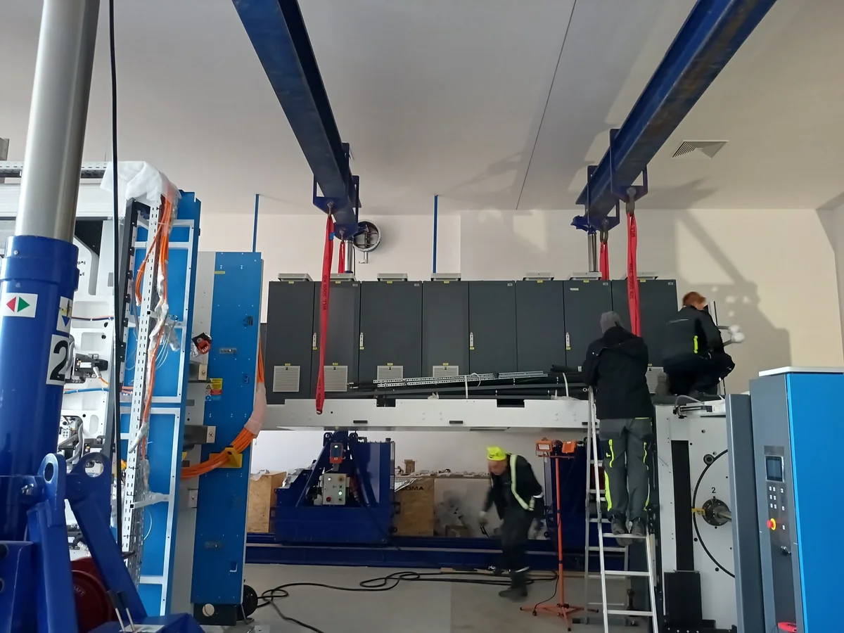 Tiskové zařízení SOMA mezi hydraulickými zvedacími portály.